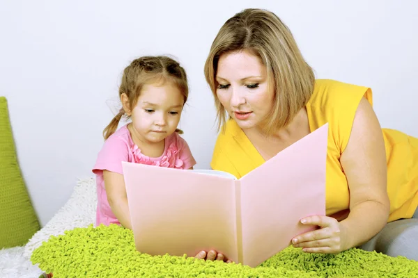 Маленькая девочка с мамой читала книгу в постели — стоковое фото
