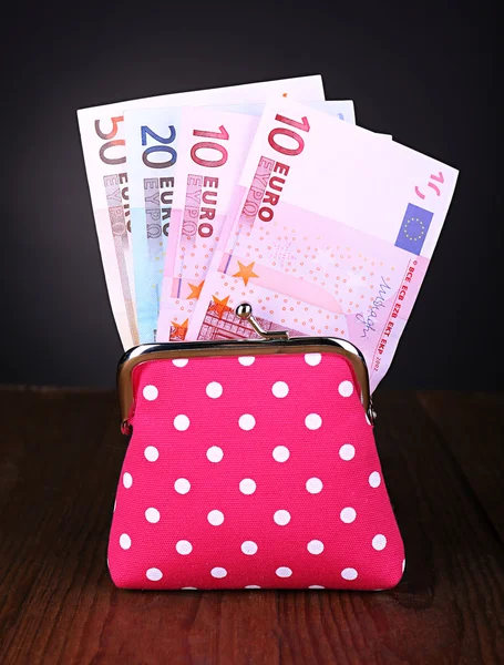 Borsetta rosa con soldi sul tavolo su sfondo nero — Foto Stock
