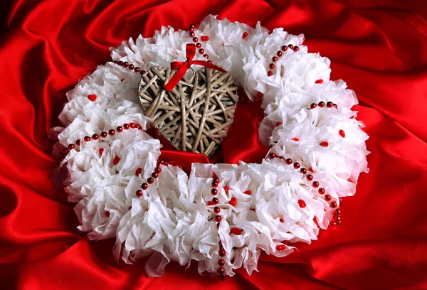 Grinalda decorativa com coração de vime no fundo do tecido — Fotografia de Stock