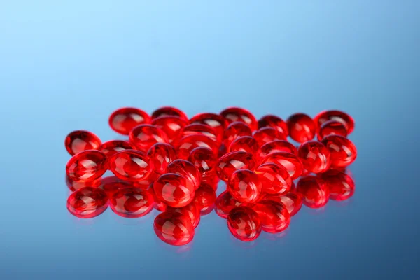 Червоні таблетки на синьому фоні крупним планом — стокове фото