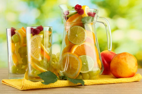 Glas und Gläser mit Zitrusfrüchten und Himbeeren auf grünem Hintergrund — Stockfoto