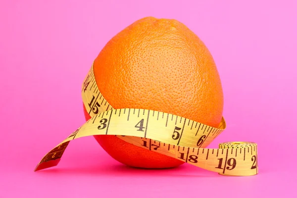 Orange with measuring tape on pink background — Stock Photo, Image