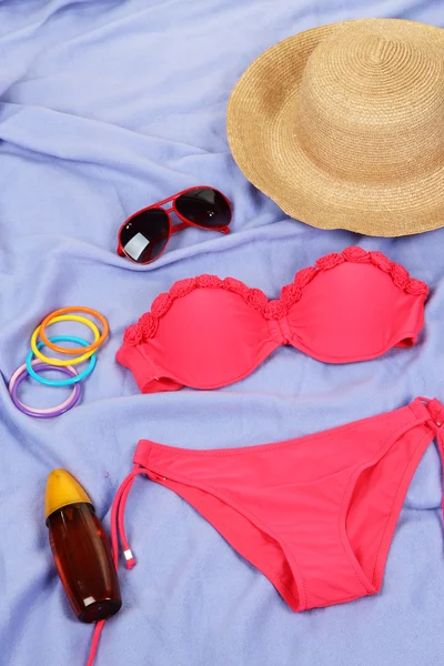 Swimsuit and beach items on purple background — Stock Photo, Image