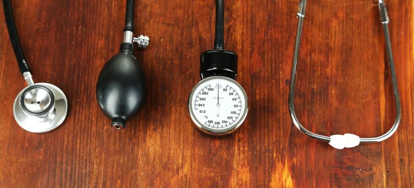 Tonometer and stethoscope on wooden table close-up — Stock Photo, Image