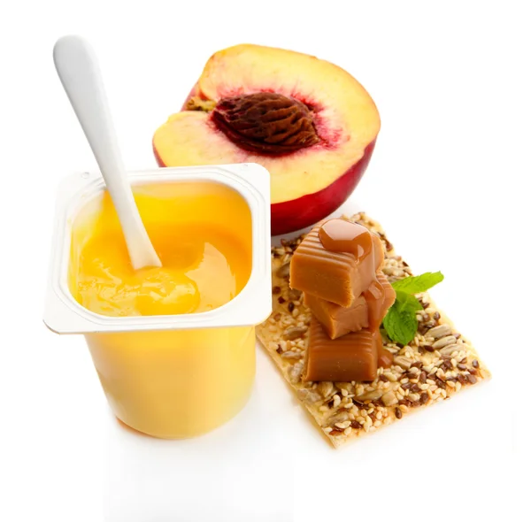 Chutné jogurt s kousky čerstvého ovoce, sušenky a cukroví karamely izolované na bílém — Stock fotografie