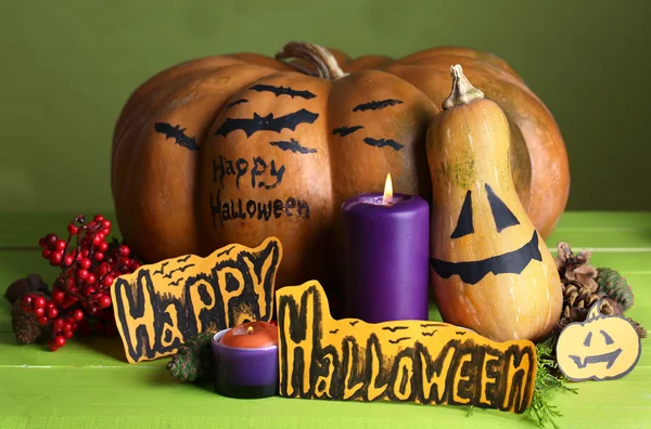Композиция на Хэллоуин с тыквами и свечами на деревянном столе на цветном фоне — стоковое фото