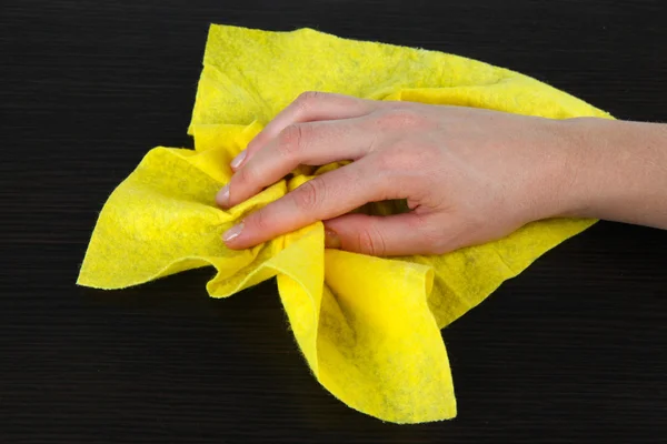 Mão limpando a superfície de madeira com pano amarelo — Fotografia de Stock