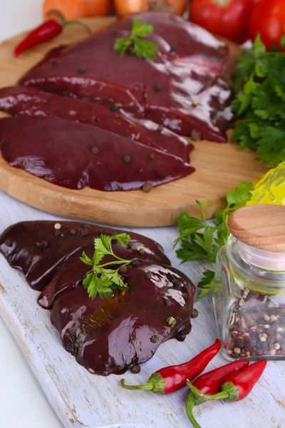 Hígado crudo sobre tabla de madera con especias y condimentos aislados sobre blanco — Foto de Stock