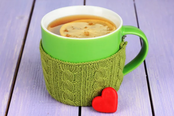 Cup with knitted thing on it on wooden table close up — Stock Photo, Image