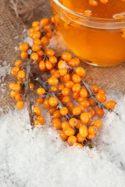 Branches of sea buckthorn with tea and snow on sackcloth background — Stock Photo, Image