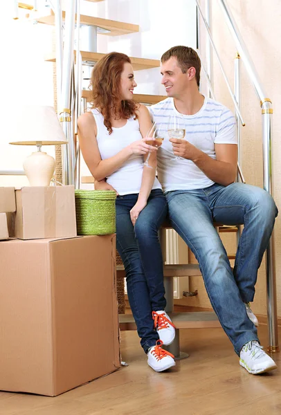 Pareja joven celebrando mudarse a su nuevo hogar sentado en las escaleras — Foto de Stock