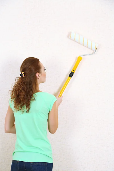 Jovem mulher pinta parede em novo apartamento — Fotografia de Stock