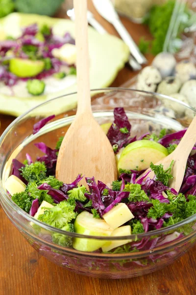 Salada de legumes frescos em tigela e prato em guardanapo em mesa de madeira close-up — Fotografia de Stock