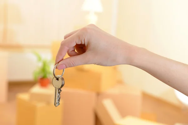 Mão feminina com teclas ob pilha de caixas de fundo: conceito de casa em movimento — Fotografia de Stock