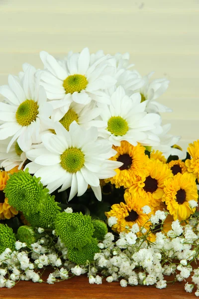 Beautiful flowers on table on wooden background — Stock Photo, Image