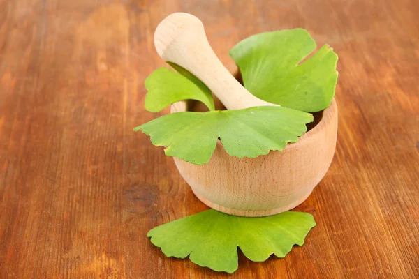 Ginkgo biloba leaves in mortar and pills on wooden background — Stock Photo, Image