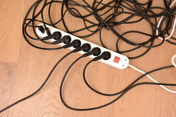 Overloaded power boards, on wooden floor background