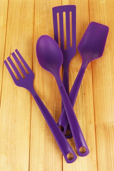 Plastic kitchen utensils on wooden background — Stock Photo, Image