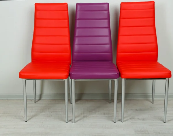 Moderní barevné židle na zeď na pozadí — Stock fotografie