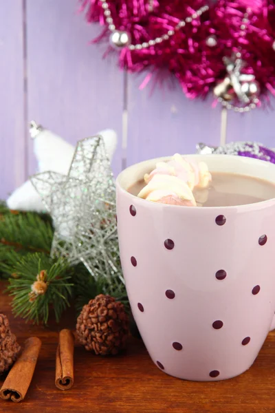 Cup of hot cacao with chocolates and Christmas decorations on table on wooden background