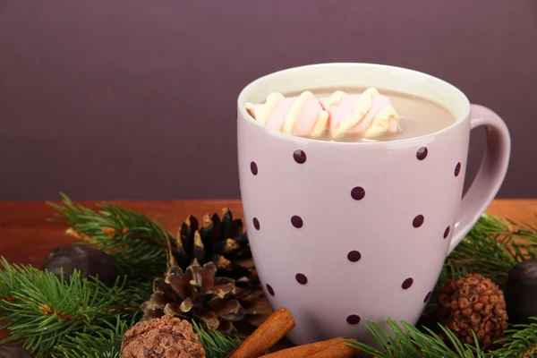 Cup of hot cacao with chocolates and fir branches on table on dark background