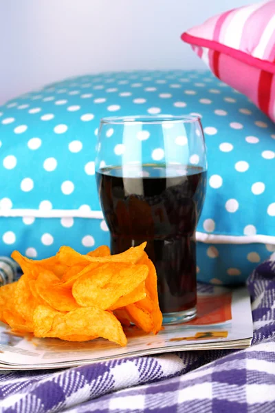 Chips in der Schüssel, Cola und TV-Fernbedienung auf karierten Kissen Hintergrund — Stockfoto