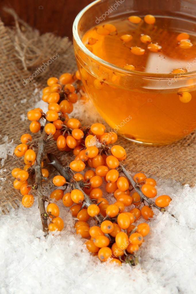 Branches of sea buckthorn with tea and snow on sackcloth background
