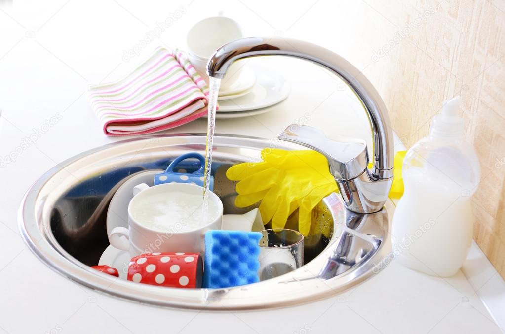 Stack of dishes soaking in kitchen sink