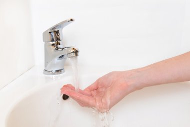 insan elinin altında beyaz izole musluk banyo, yıkandıktan Close-Up