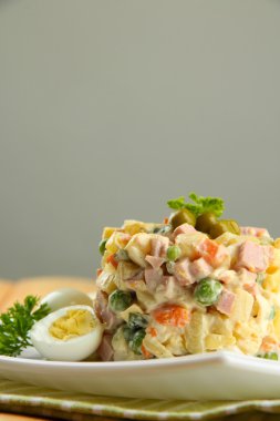 geleneksel Rus salatası olivier, tahta masada gri arka plan üzerinde renkli peçete üzerinde