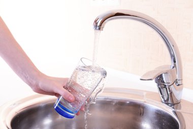 mutfak musluk elini tutarak bardak su döktü