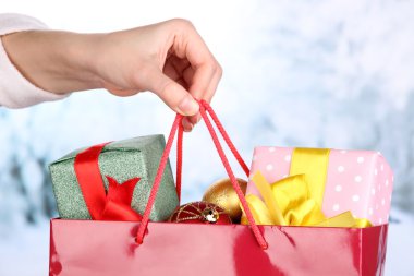 el ile yeni yıl topları ve hediye paketi kar arka planda tutar.