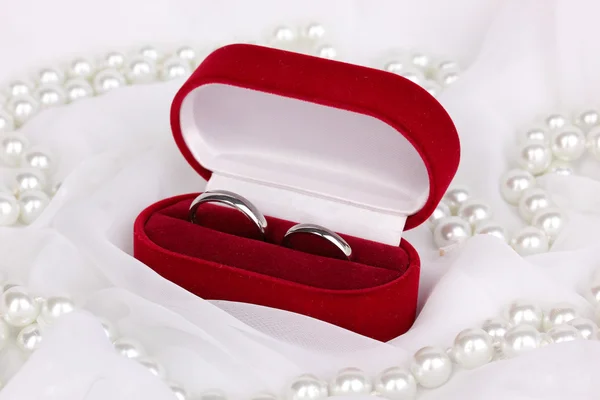 Anillos de boda en caja roja sobre fondo de tela blanca — Foto de Stock