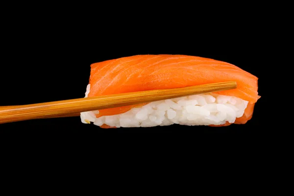 Hålla sushi med pinnar isolerade på svart — Stockfoto