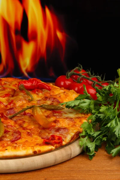 Gustosa pizza al peperoncino con verdure su tavola di legno su fondo fiamma — Foto Stock