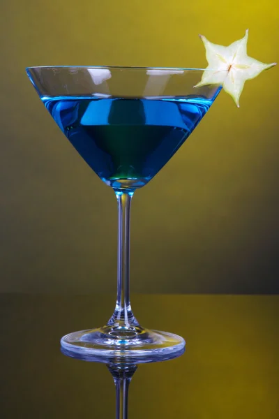 Blue cocktail in martini glass on dark yellow background — Stock Photo, Image