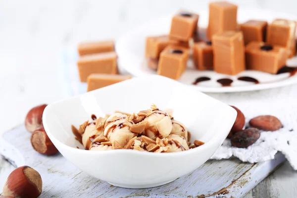 Many toffee on plate and in bowl on napkin on board close-up — Stock Photo, Image