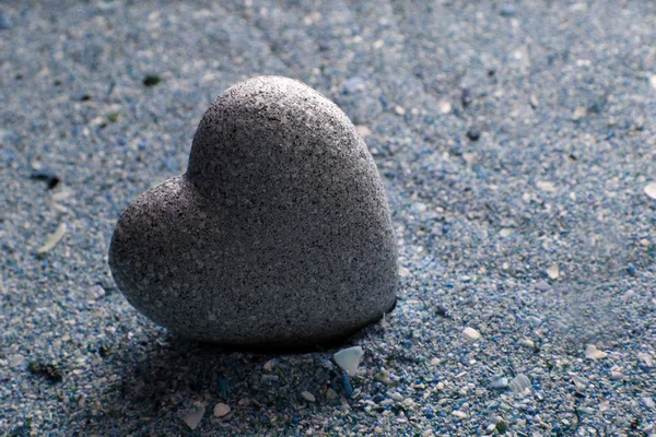 Grey stone in shape of heart, on sand background — Stock Photo, Image