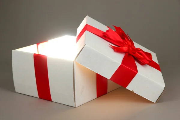 Geschenkbox mit hellem Licht auf grauem Hintergrund — Stockfoto
