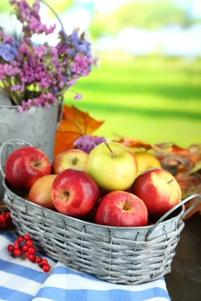 Juicy apples in basket on table on natural background — Stock Photo, Image