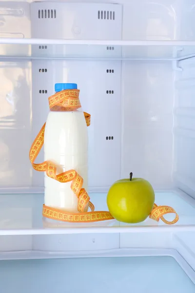 Концептуальное фото диеты: бутылка яблока и молока с измерительным типом на полке холодильника — стоковое фото