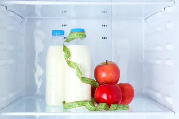 Konceptuální fotografie stravy: apple a mléko láhev s měřením typu na police chladničky — Stock fotografie