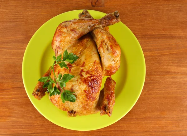 Roasted whole chicken on a green plate on wooden background — Stock Photo, Image