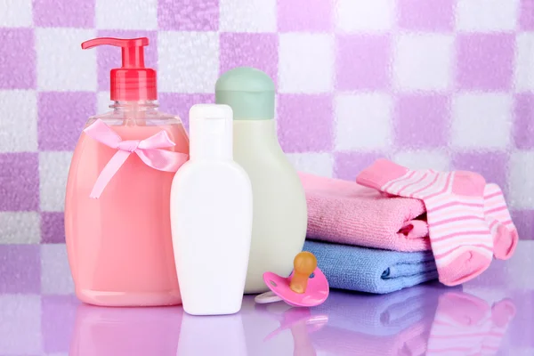 Baby cosmetics and towels in bathroom on violet tile wall background — Stock Photo, Image