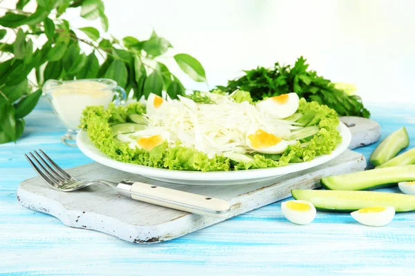 Deliziosa insalata con uova, cavolo e cetrioli sul tavolo di legno blu — Foto Stock