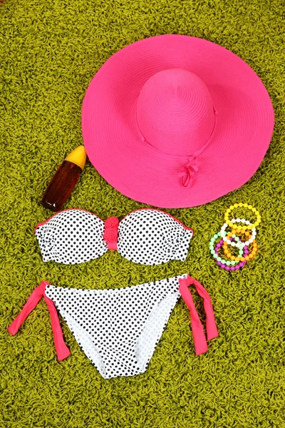 Swimsuit and beach items on green background — Stock Photo, Image