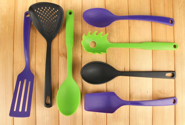Plastic kitchen utensils on wooden background — Stock Photo, Image