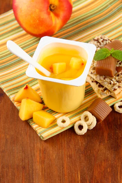 Lekkere yoghurt met stukken van vers fruit, cookies en vlokken, op houten achtergrond — Stockfoto