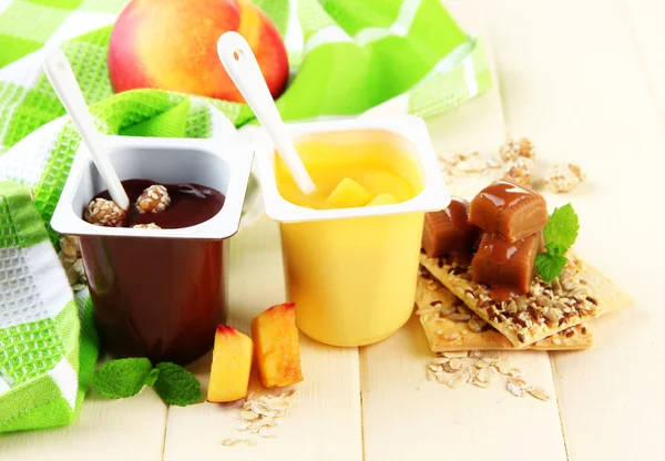 Sabrosos postres de crema con trozos de fruta fresca, galletas y copos, sobre fondo de madera de color — Foto de Stock