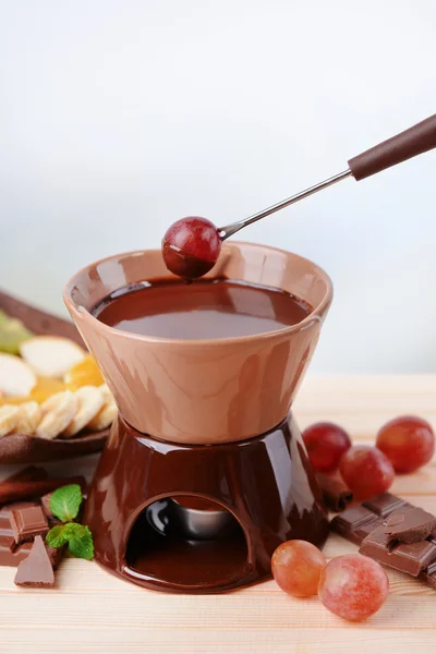 Chokladfondue med frukt, på träbord, på ljus bakgrund — Stockfoto